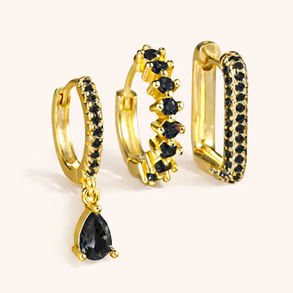 The Fia SET is shown in a black crystal colorway across its drop huggie, zigzag hoop, and pave rectangle hoop.