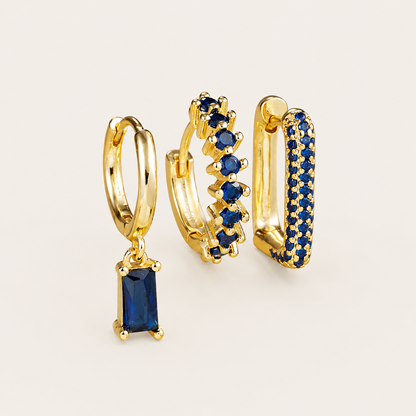 The Fia SET is shown in a deep blue colorway, with a baguette drop huggie, zigzag hoop, and pave rectangle hoop.