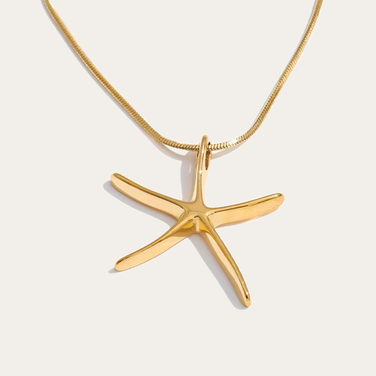 The Fiji NECKLACE in gold, its sculptural starfish pendant shown alone on a fine snake chain against a plain studio background.