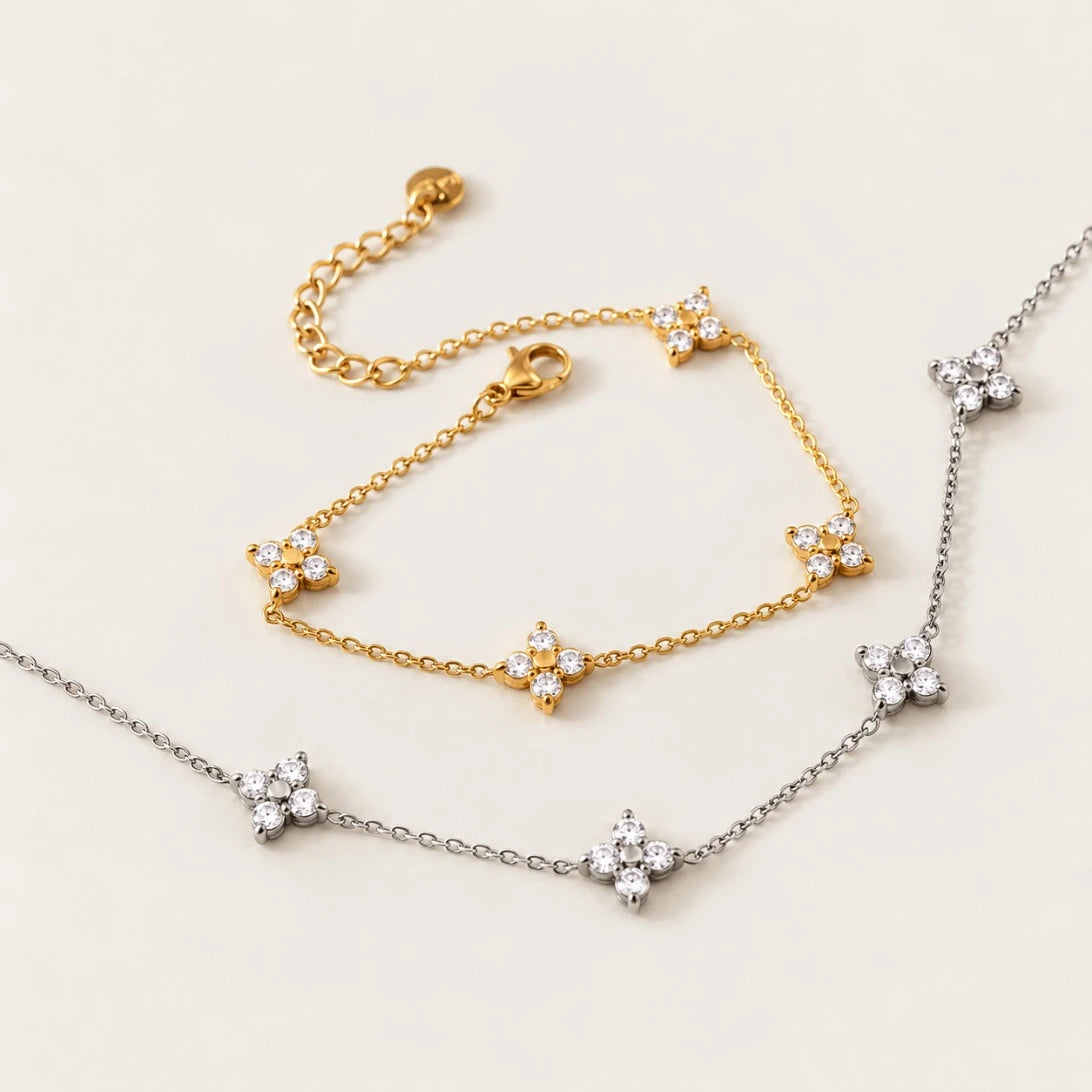 Silver-tone Fiore NECKLACE with zirconia flowers beside a gold Fiore bracelet on a cream background — Folie à Trois