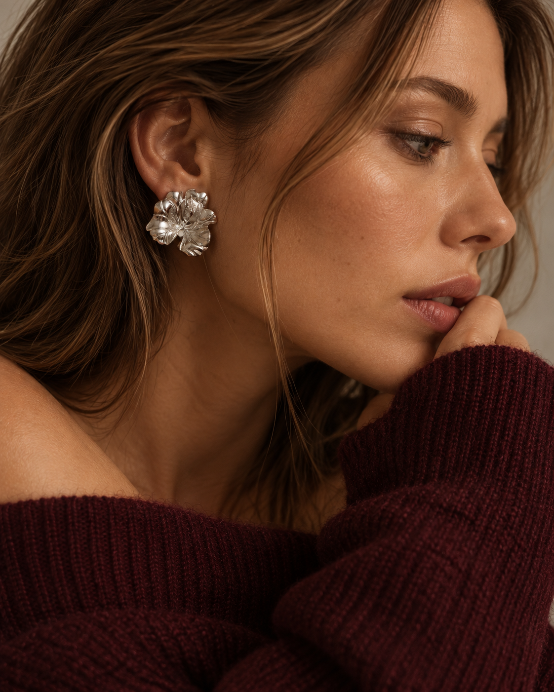Editorial profile of a woman wearing silver-tone Fleurette flower EARRINGS with a burgundy knit sweater — Folie à Trois