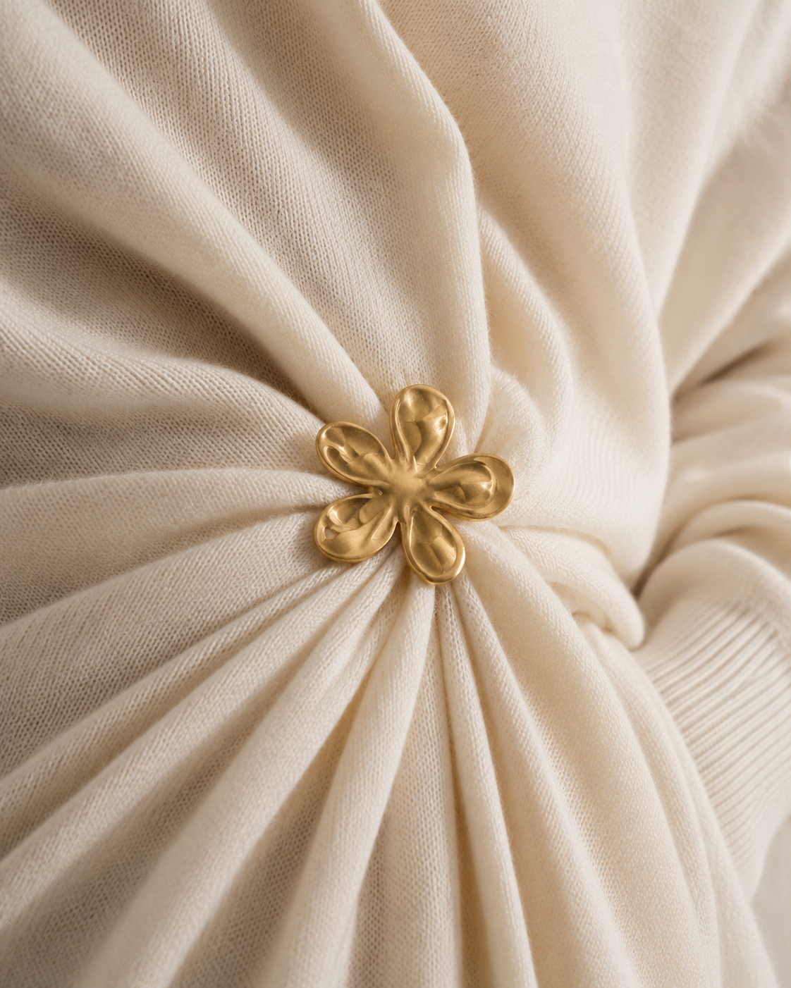 Close-up of a gold Flora BROOCH cinching draped cream knit fabric — Folie à Trois wholesale jewelry