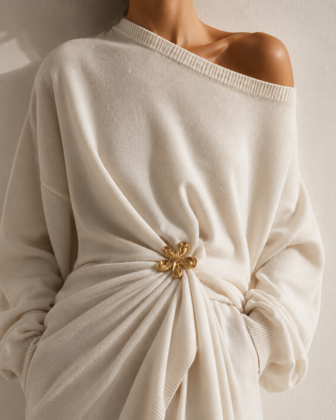 Model wears a gold Flora BROOCH gathering a cream off-shoulder sweater at the waist — Folie à Trois
