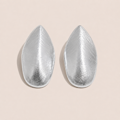Silver leaf-shaped stud earrings with a brushed textured finish on a cream backdrop — Folie à Trois Foglia EARRINGS