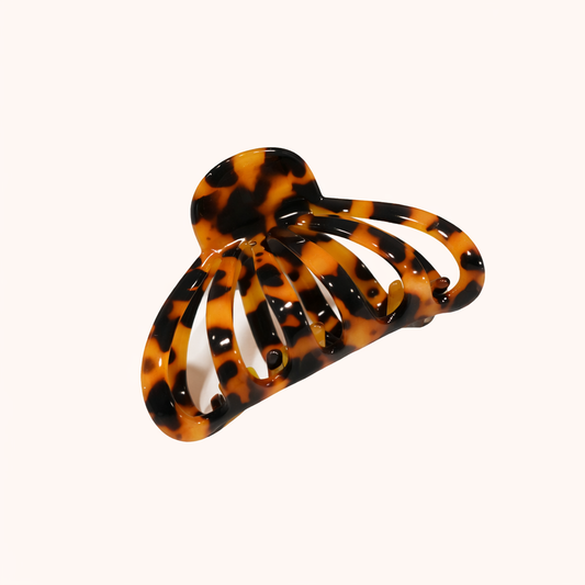 Amber and black tortoiseshell open-lattice claw clip from the Forget About Me HAIR CLIP collection, shown on a cream studio background.