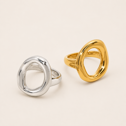 Silver and gold Formentera RING side by side, each an open organic asymmetric loop with a chunky polished band, on a cream backdrop.