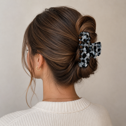 French Girl HAIR CLIP's black and white confetti claw clip worn in a low bun, styled with gold hoop earrings.