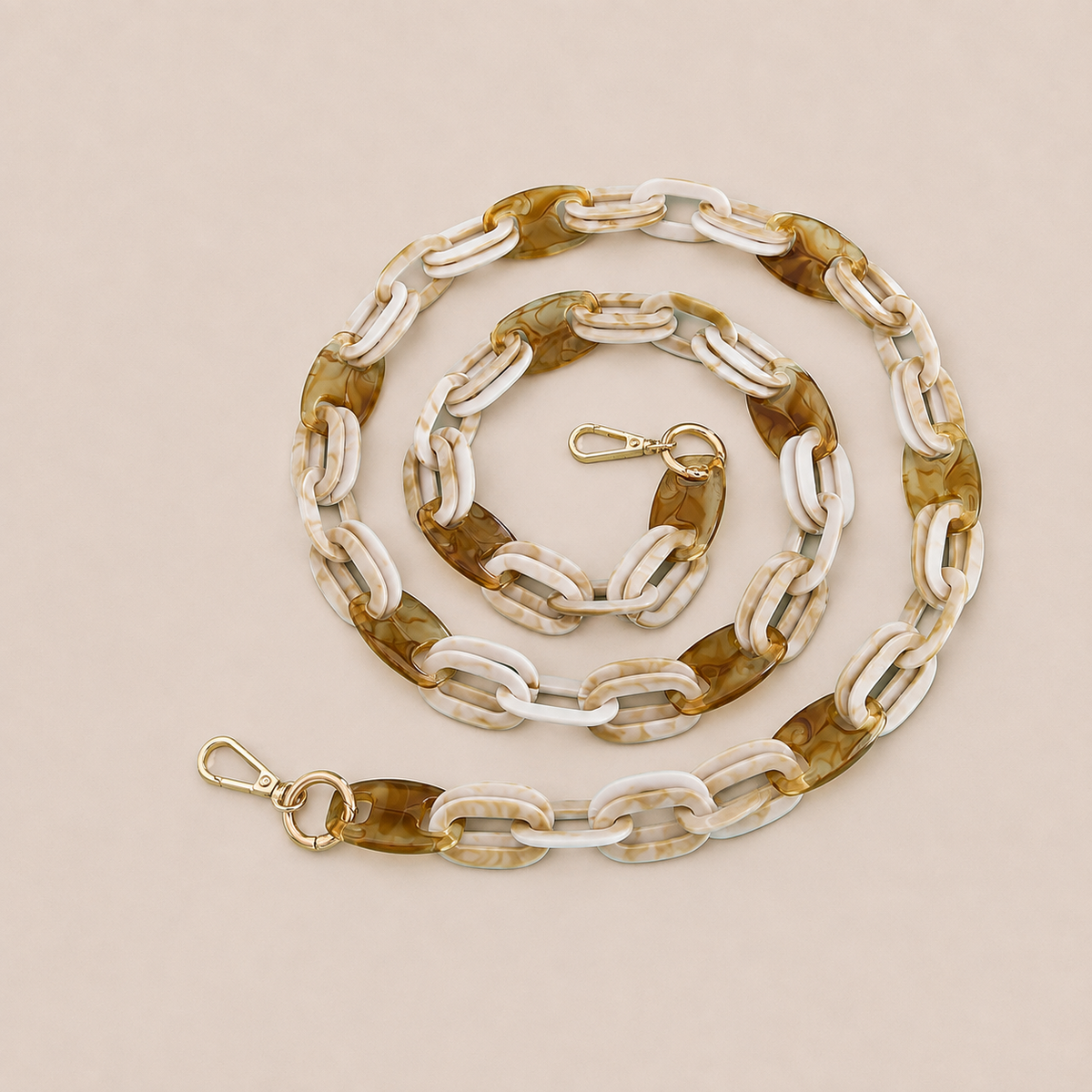 Folie à Trois Frost long wholesale phone chain in white and tan marbled acetate links with gold clasps, coiled on a cream background.