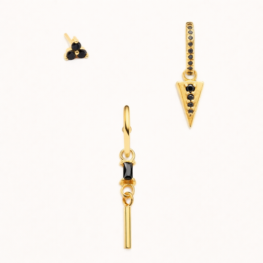 The Gabriella SET in gold with black onyx stones, featuring a triple-dot stud, a pavé triangle dangle hoop, and a bar-dangle hoop in studio.