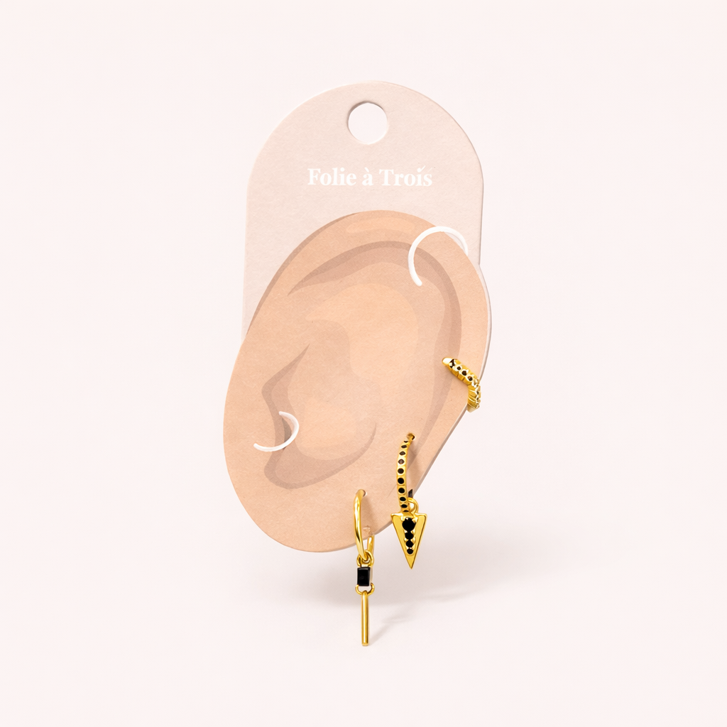 The Gabriella SET in gold with black onyx displayed on a branded Folie à Trois ear card with the stud, triangle hoop, and bar-dangle hoop.
