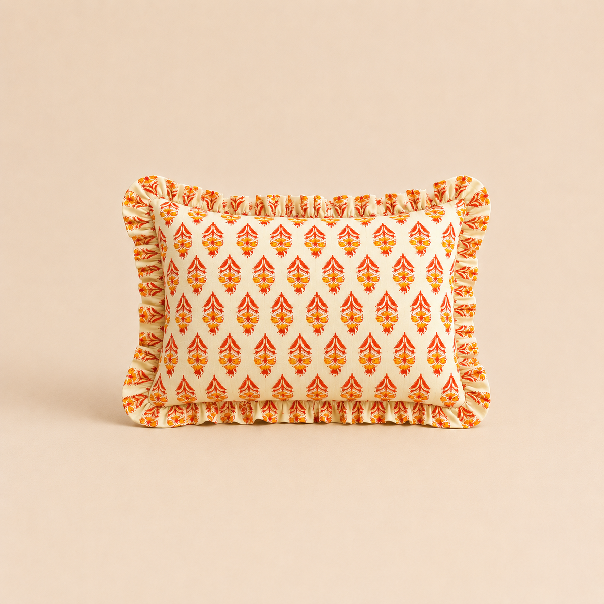Garnet Blossom Rectangle cushion in cream with a red and orange block-print floral pattern, trimmed with a soft ruffled edge.