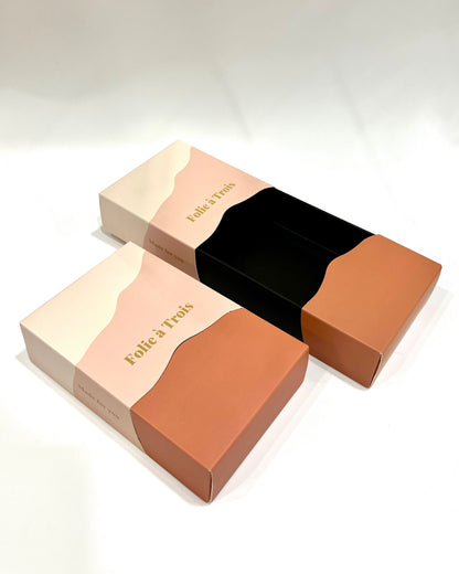 Two open rust and cream gift boxes side by side revealing their black velvet jewelry inserts.