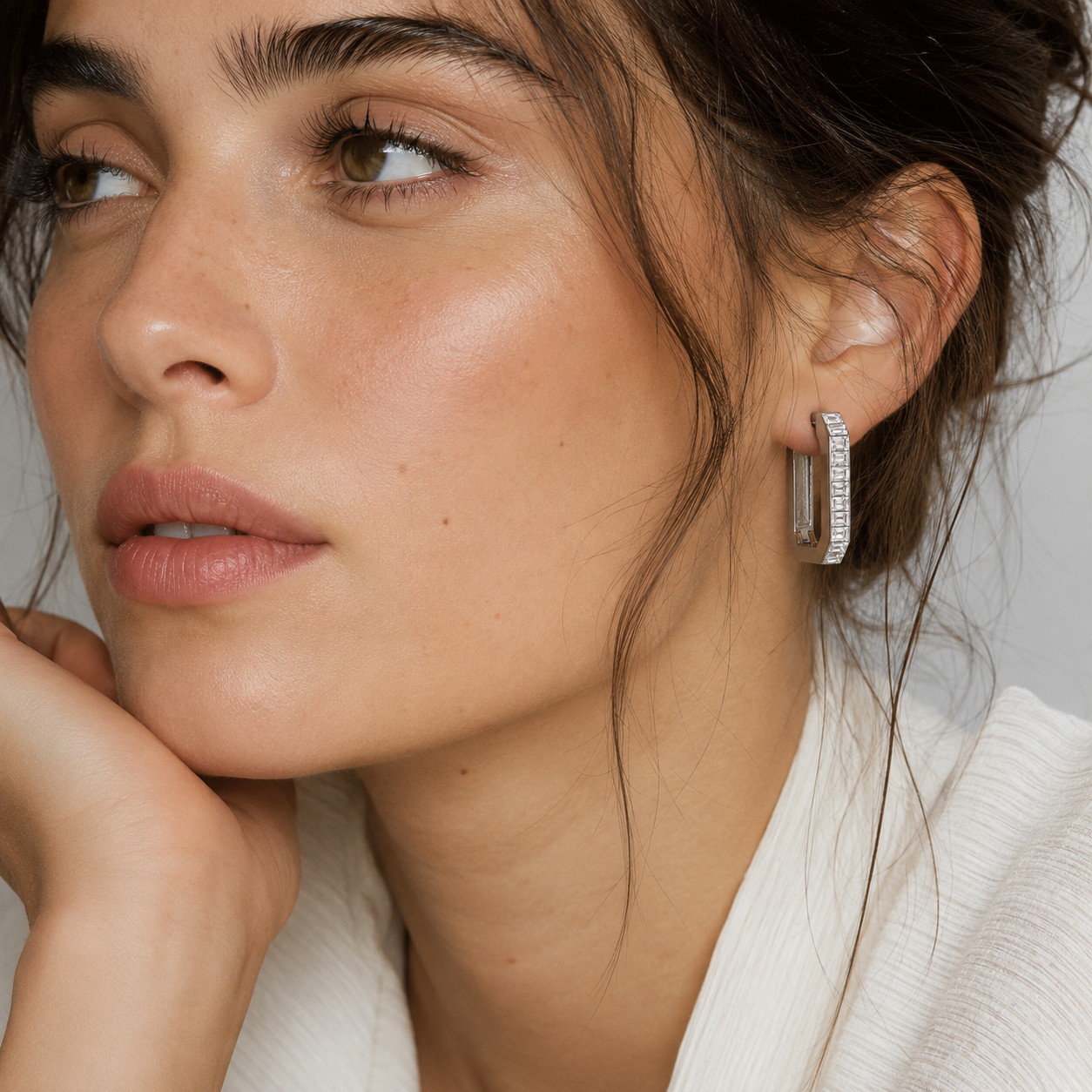 Model wears the silver Folie à Trois Girasole EARRINGS, a rectangular hinged hoop channel-set with emerald-cut zirconia stones.