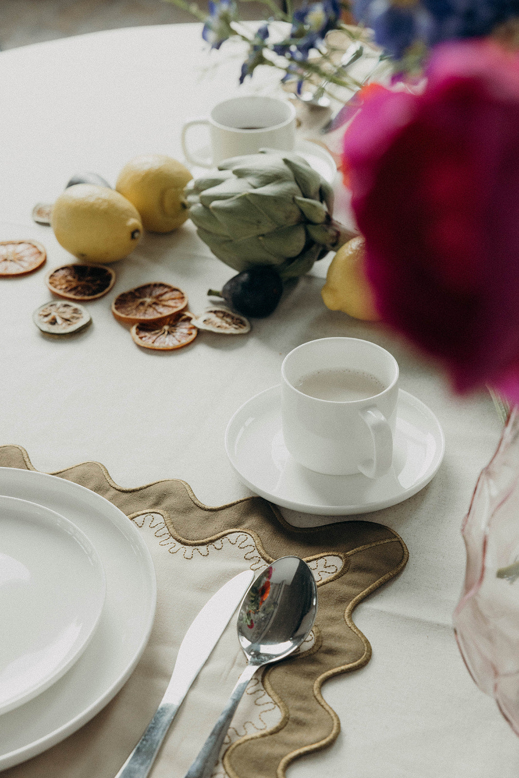 Orange placemat with white and lilac scalloped stitching, a colorway of the Gisèle Scallop placemat with embroidered detail.