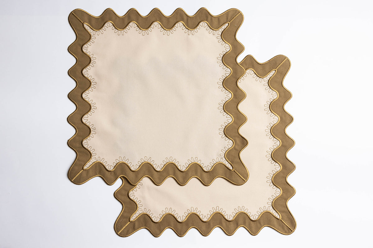 Close-up of a folded olive-green napkin with a cream piped scalloped edge, from the Gisèle Scallop napkins with embroidered detail.