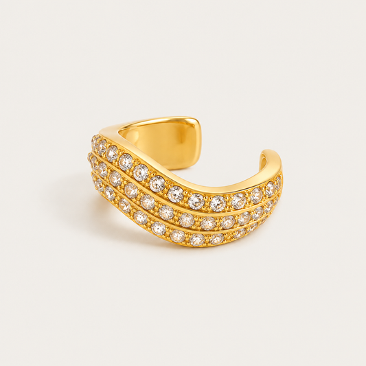 Gold wavy ear cuff set with three rows of sparkling zirconia pavé on a cream background — Folie à Trois wholesale jewelry