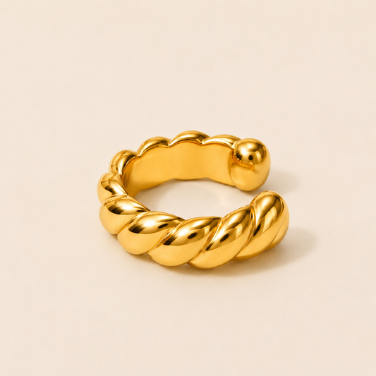 The Golden Hour EAR CUFF in a studio flat lay, a chunky gold cuff with a twisted rope texture on a cream background.
