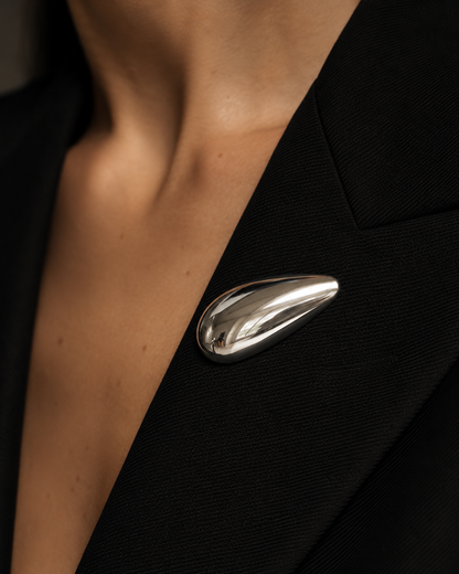 Close-up of a silver teardrop Gota BROOCH pinned to the lapel of a black blazer — Folie à Trois wholesale jewelry