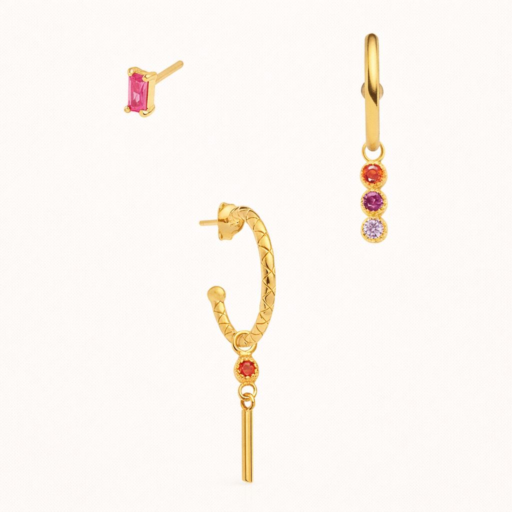 The Gretta SET in gold with pink, red, and purple stones, featuring a baguette stud, a bar-dangle hoop, and a three-stone hoop in studio.
