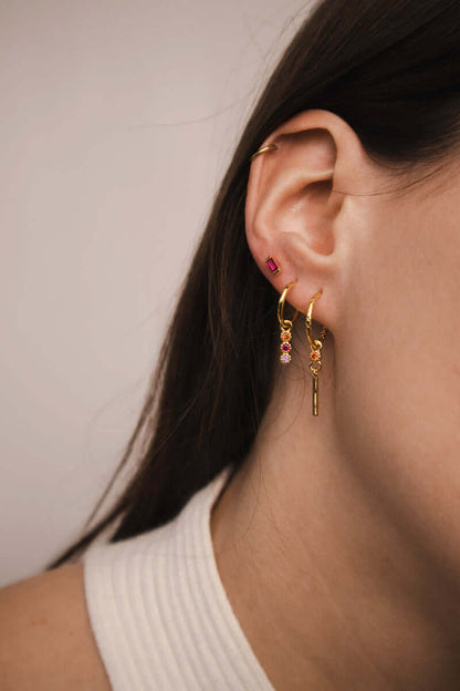 A model wears the Gretta SET in gold, layering the braided bar-dangle hoop with the three-stone dangle hoop along the ear.