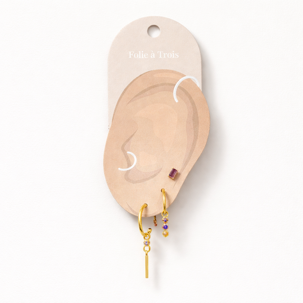 The Gretta SET in gold displayed on a branded Folie à Trois ear card with the baguette stud, bar-dangle hoop, and three-stone dangle hoop.