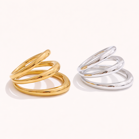 Gold and silver Harley RING styles, each with three interlocking smooth bands, shown together on a cream backdrop.
