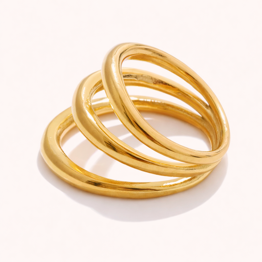 Gold Harley RING with three interlocking smooth bands, shown at an angle on a cream backdrop.