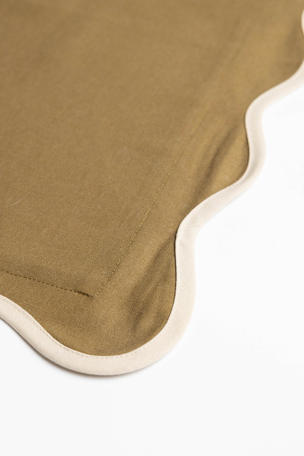 Macro detail of the Harper Linen cushion's scalloped edge, showing olive-green fabric bordered with gold embroidered stitching.