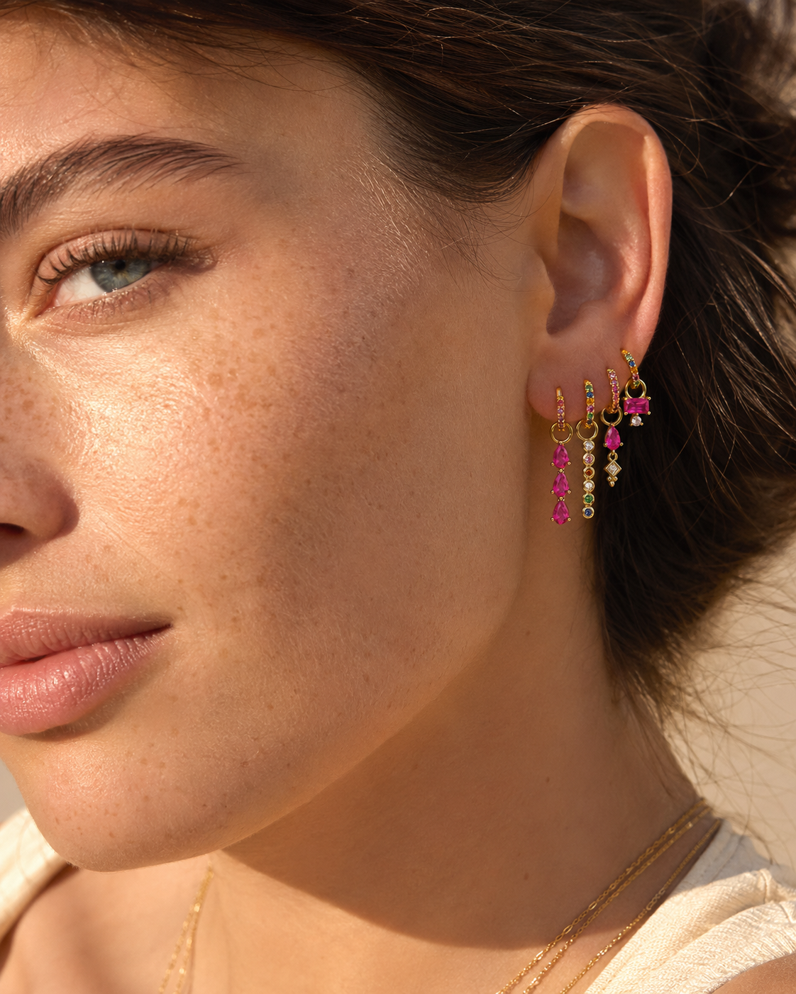 Harper Set worn outdoors in profile, showing the stacked huggie hoops with ruby and multicolor gemstone drops.