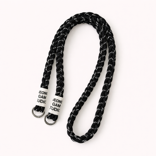 Black braided cord Havana long phone strap with fleck detailing, coiled with silver ring hardware.