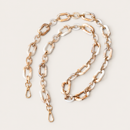 The Hazel LONG PHONE CHAIN in cream-and-tan marbled rectangular-link acrylic with gold-tone clasp ends, coiled on a beige background.
