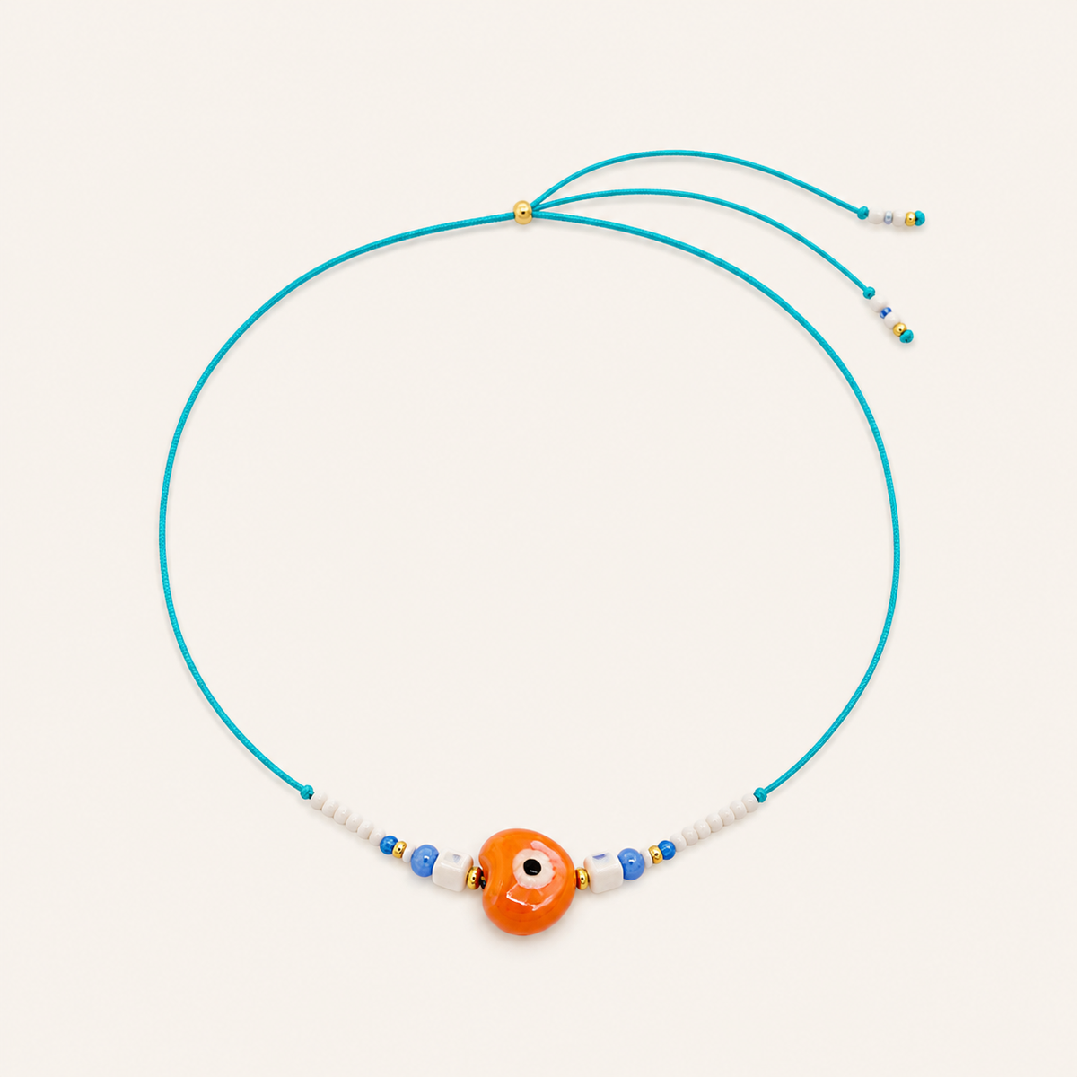 Blue cord Heart Eye NECKLACE with beaded white and navy accents around an orange enamel evil eye charm, laid flat.