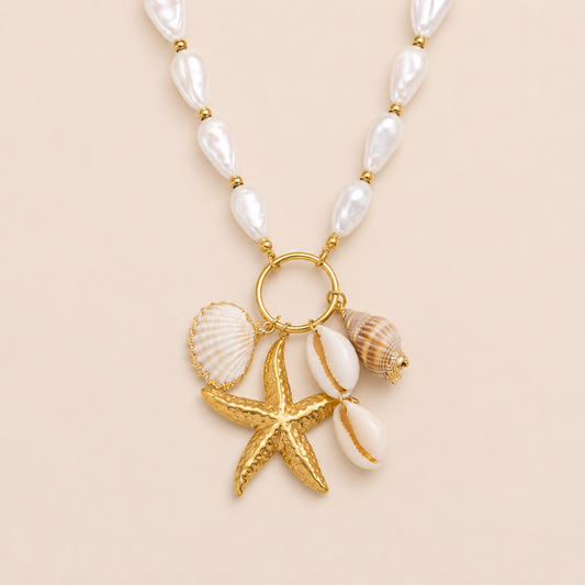 Horizon NECKLACE with a freshwater pearl chain holding gold starfish, cowrie, scallop and conch shell charms.