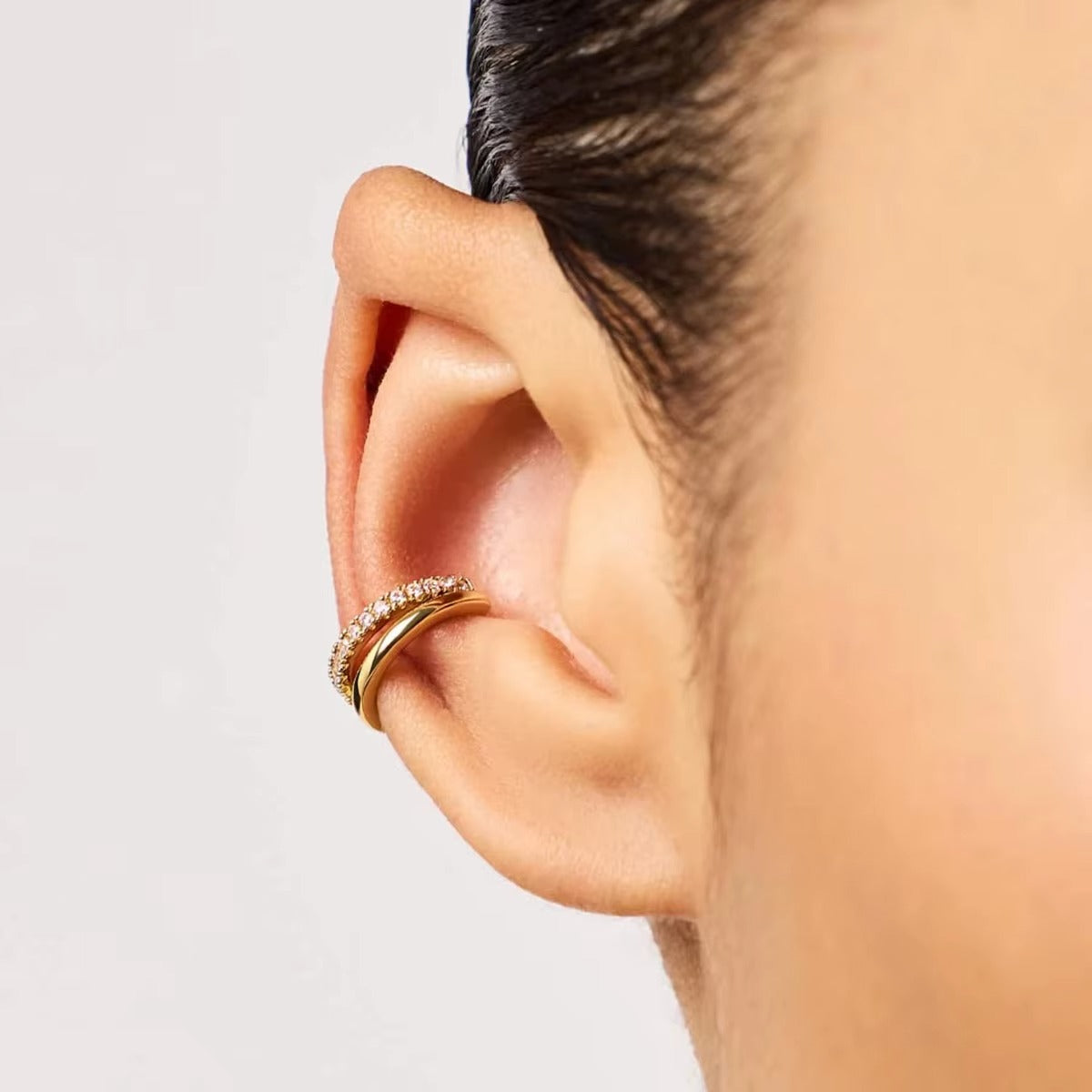 Hotline Ear Cuff worn on the ear cartilage of a model with sleek dark hair, showing the smooth and pave crystal bands wrapped together.