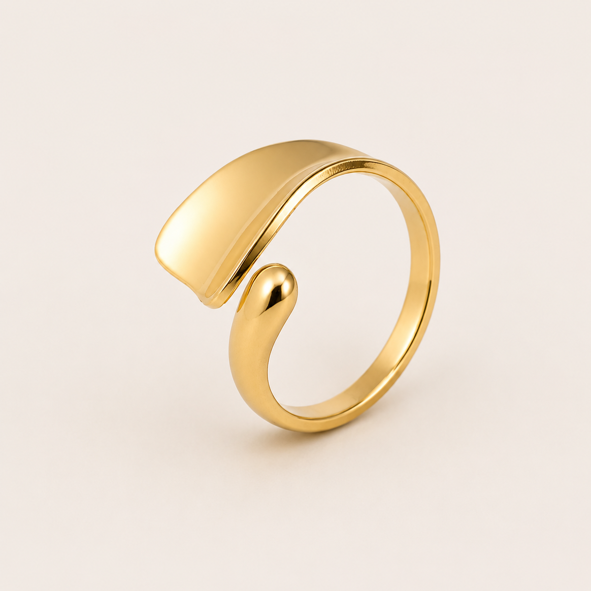 Gold open ring with an asymmetric teardrop-shaped panel overlapping a slim curved band, shown on a cream backdrop — Folie à Trois Hydra RING.