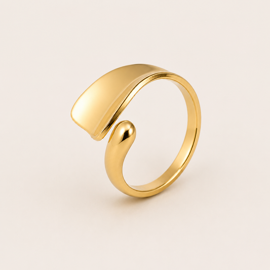 Gold open ring with an asymmetric teardrop-shaped panel overlapping a slim curved band, shown on a cream backdrop — Folie à Trois Hydra RING.