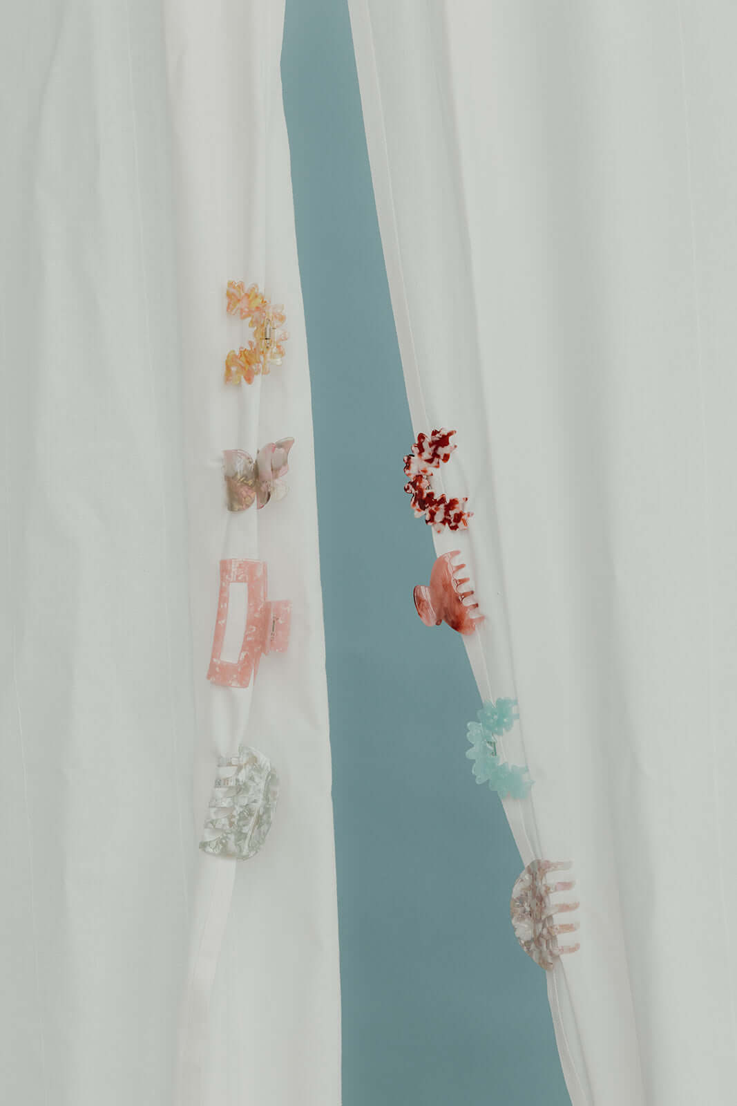 Assorted acetate hair clips in bow, butterfly and flower shapes hanging on a sheer curtain, a generic collection shot rather than an Ice Queen photo.