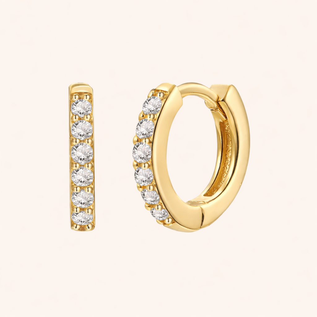 In a Dream Earrings in gold with clear crystals, showing the six-stone pave huggie hoop design.