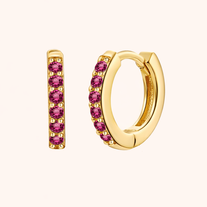 In a Dream Earrings in gold with fuchsia-pink crystals, showing the six-stone pave huggie hoop design.