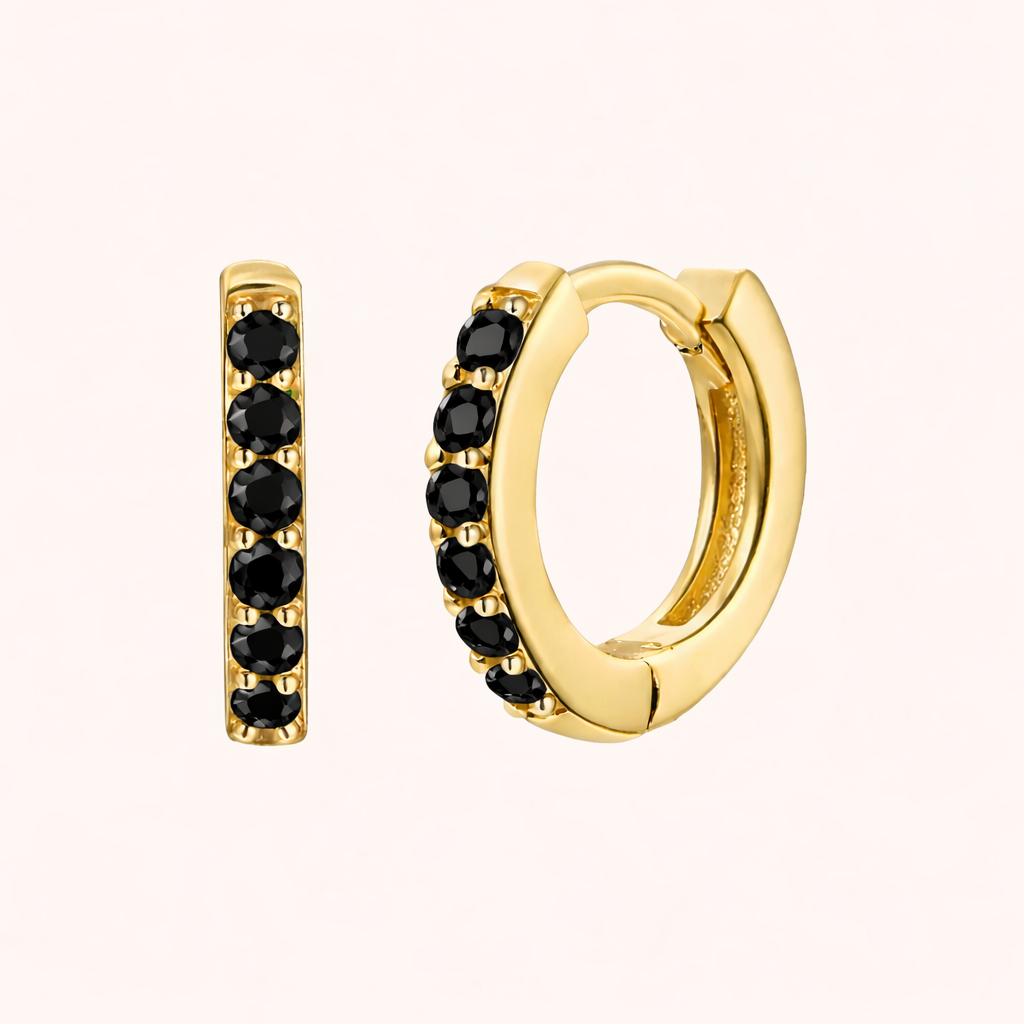 In a Dream Earrings in gold with black crystals, showing the six-stone pave huggie hoop design.