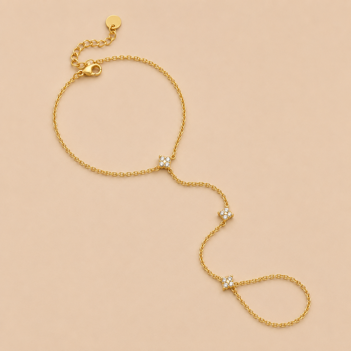 Insolite Hand Chain BRACELET in gold with a wrist chain connected to a ring by three small crystal-set stations, shown flat.