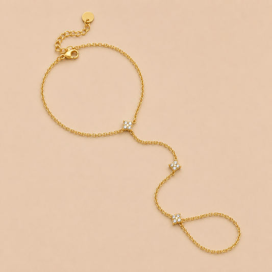 Insolite Hand Chain BRACELET in gold with a wrist chain connected to a ring by three small crystal-set stations, shown flat.