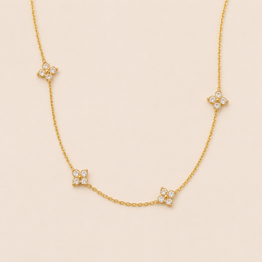 Gold chain necklace with four sparkling flower-shaped crystal clusters from the Insolite NECKLACE design, laid flat.