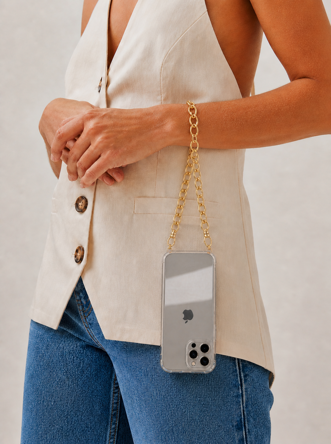 Model wears the gold chain-link Interlaced strap on her wrist, holding a clear-case phone at her hip.