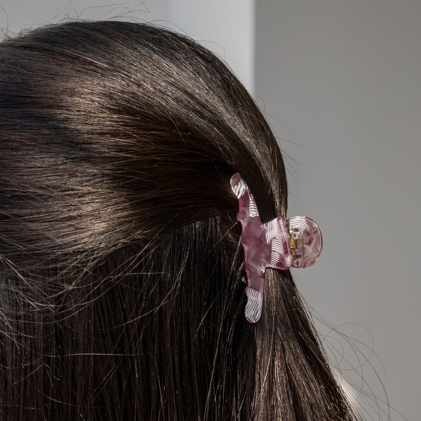 Iris HAIR CLIP in a purple and white striped pattern, worn half-up on dark hair, close-up back view.