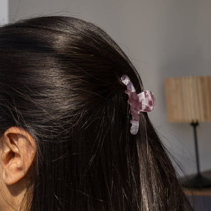 Iris HAIR CLIP in a purple and white striped pattern, worn half-up on dark hair, side view with a lamp in the background.