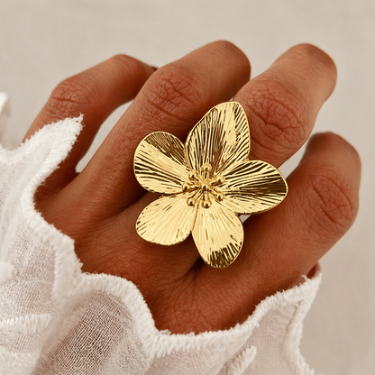Model wears the gold Isle Of Paradise RING's large flower face on her hand against a sheer white fabric.