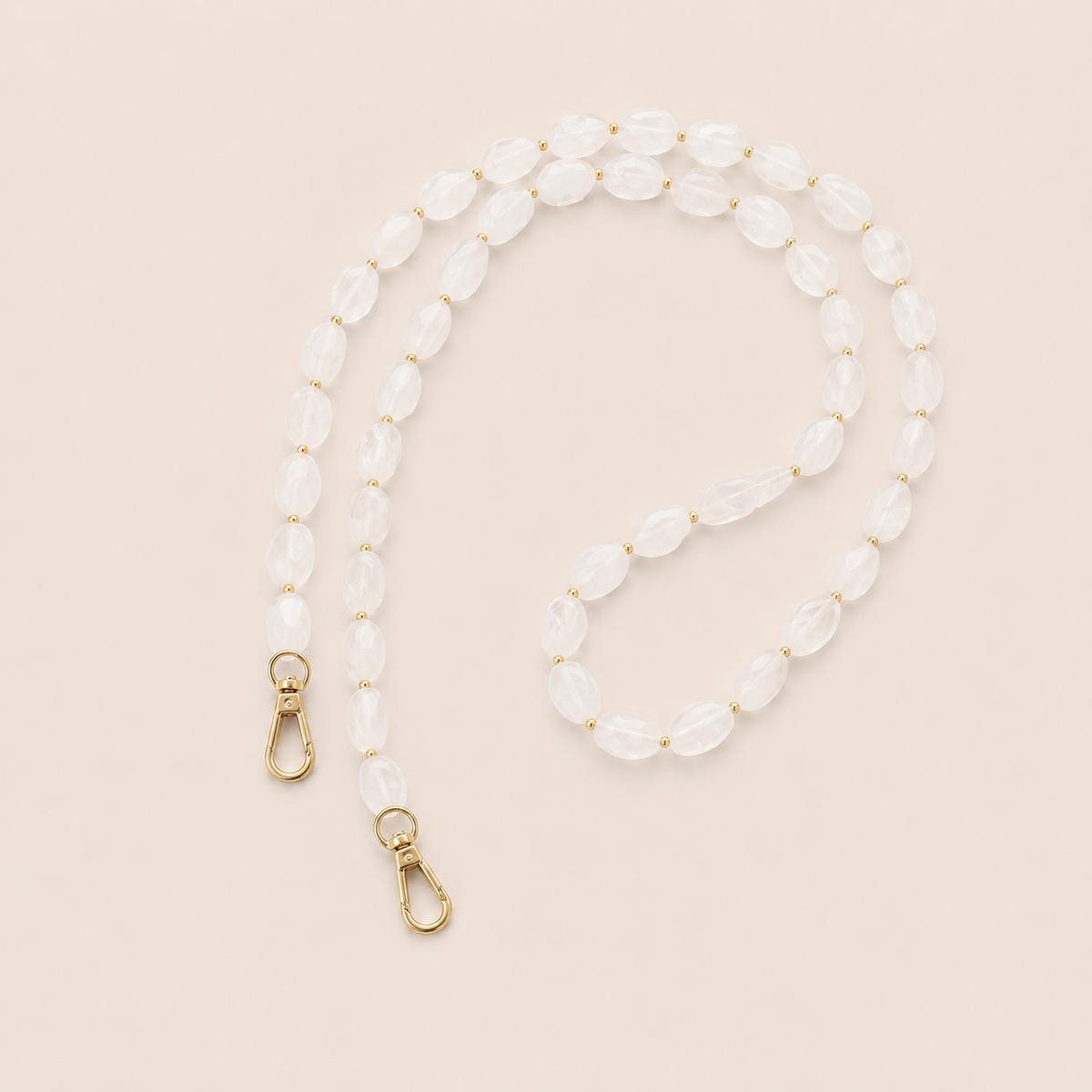 Folie à Trois Isolde long wholesale phone chain in frosted white opal beads with gold accent beads and gold clasps, styled flat on a cream background.