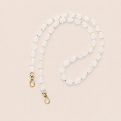Folie à Trois Isolde long wholesale phone chain in frosted white opal beads with gold accent beads and gold clasps, styled flat on a cream background.