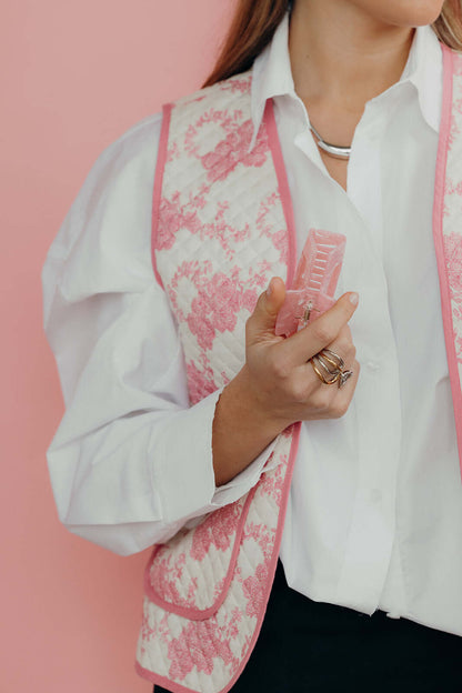 It Girl Big HAIR CLIP's pink marbled claw clip held against a pink toile jacket, styled with silver rings and a necklace.